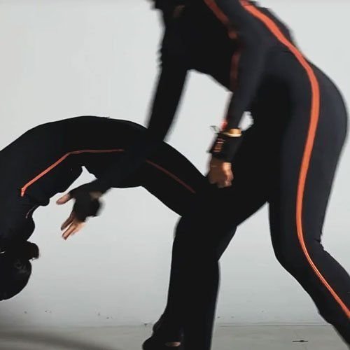 Two performers in motion capture suits rehearsing a move
