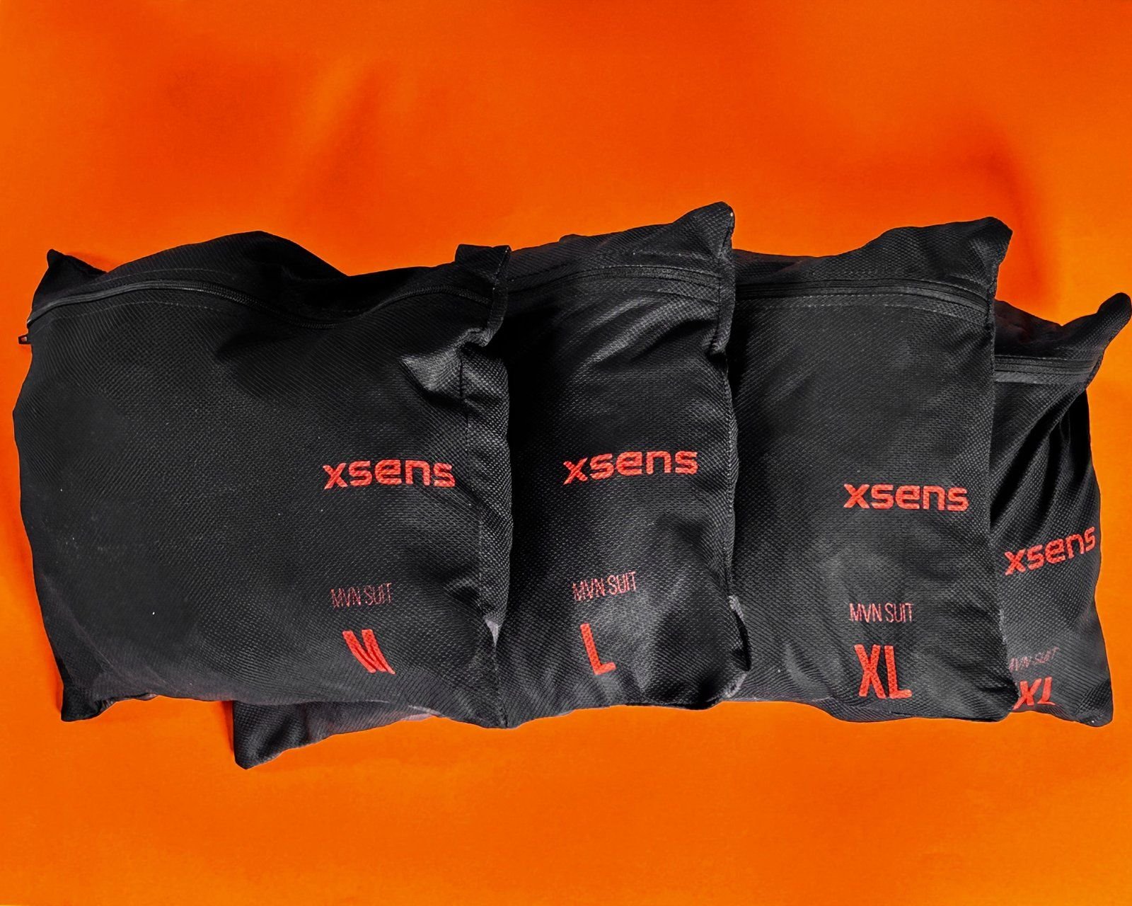 Black Xsens motion capture suits in bags on an orange background