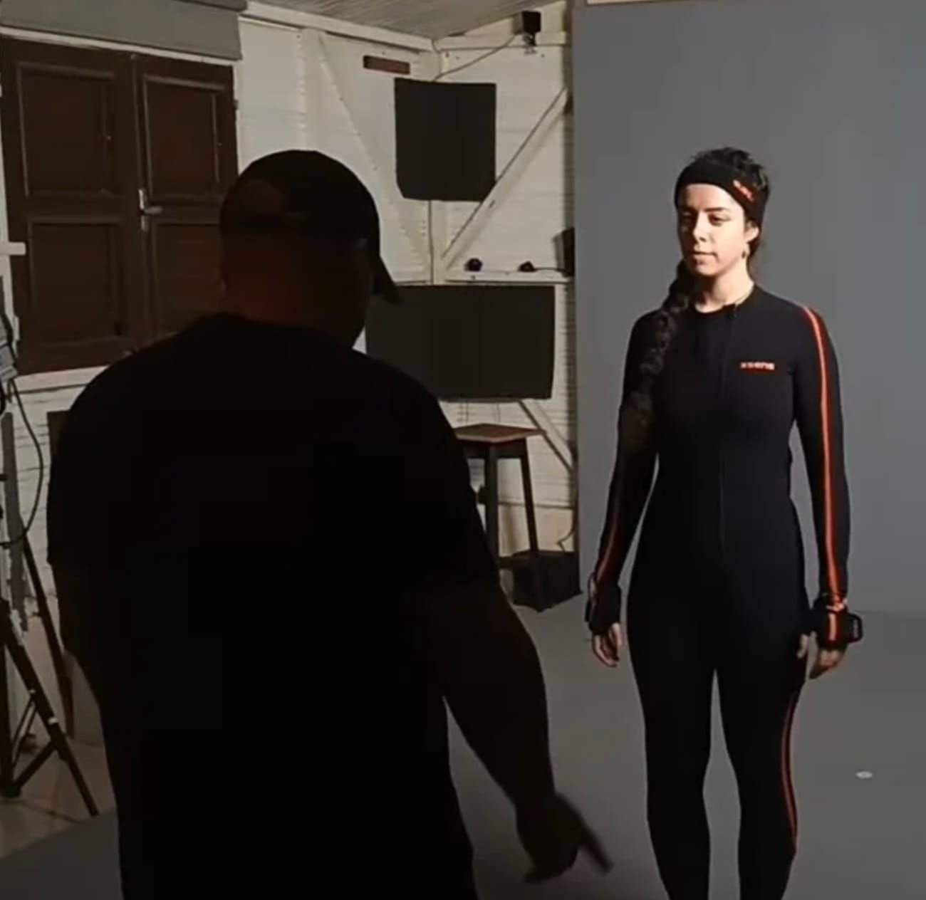 A director guiding a performer wearing a motion capture suit