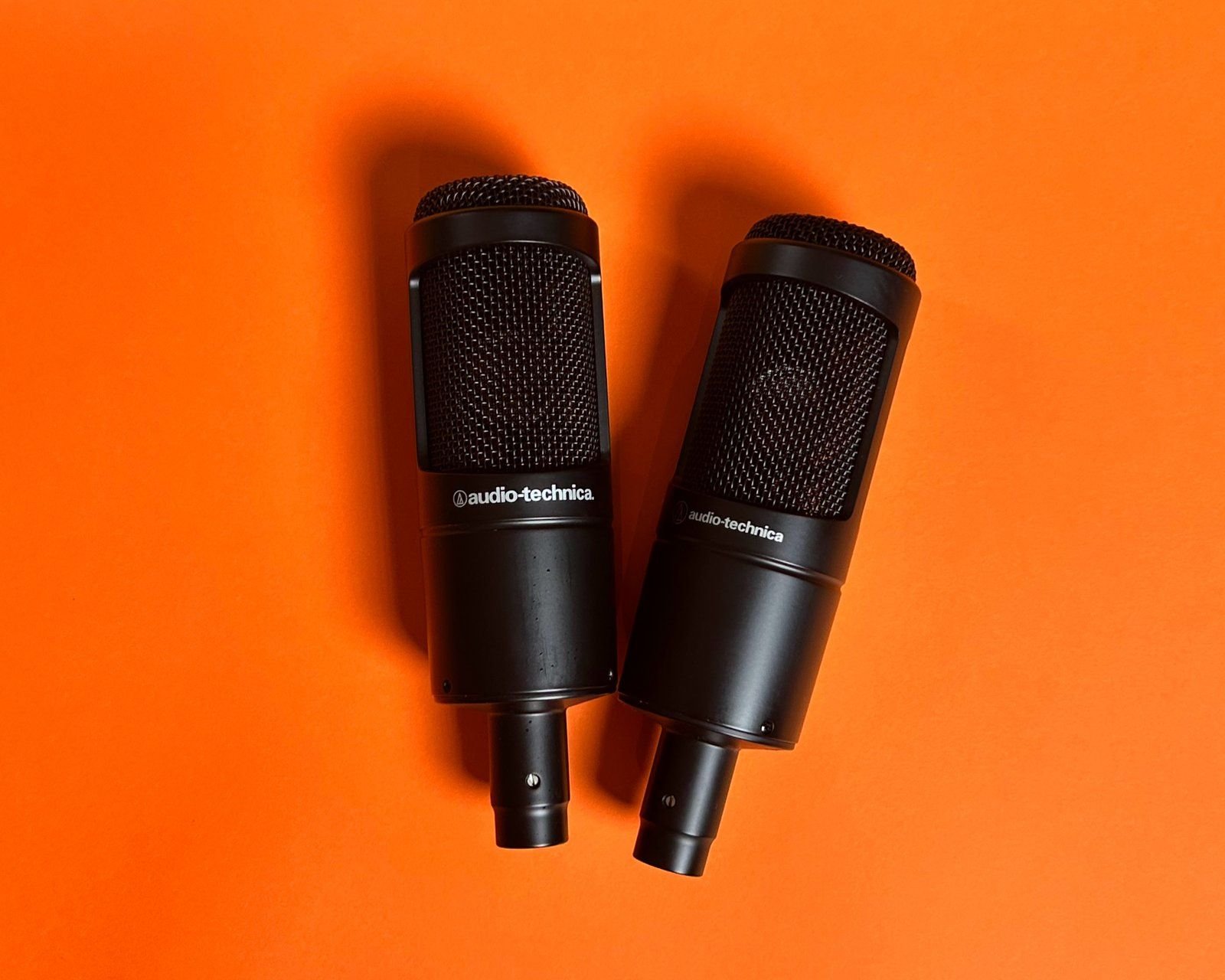 Two studio microphones on an orange background